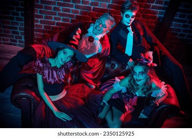 Portrait of teenage friends in carnival costumes having fun celebrating Halloween. Skeleton, witch, clown and vampire. Merry Halloween party. 