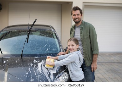 Portrait of teenage girl and father washing a car on a sunny day - Powered by Shutterstock