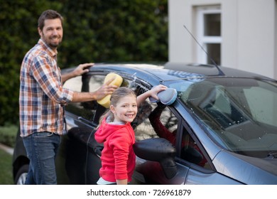 Portrait of teenage girl and father washing a car on a sunny day - Powered by Shutterstock