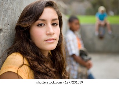 Portrait of teenage girl hanging out with friends outdoors at camera