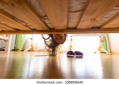 Portrait Of Teenage Girl With Long Hair Looking Under The Bed