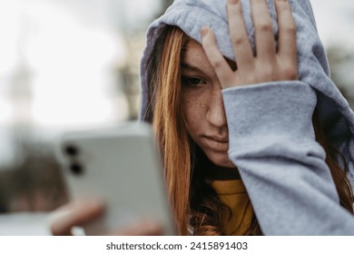 Portrait of teenage girl looking at her smartphone, sad, anxious, alone. Cyberbullying, girl is harassed, threated online. - Powered by Shutterstock