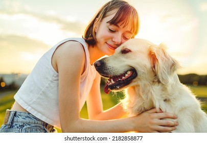 A Portrait of teenage girl petting golden retriever outside in sunset - Powered by Shutterstock