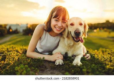 A Portrait of teenage girl petting golden retriever outside in sunset - Powered by Shutterstock