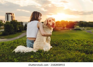 A Portrait of teenage girl petting golden retriever outside in sunset view from back - Powered by Shutterstock