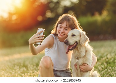 A Portrait of teenage girl petting golden retriever outside in sunset taking selfie - Powered by Shutterstock