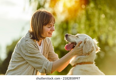 A Portrait of teenage girl petting golden retriever outside in sunset - Powered by Shutterstock