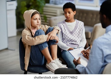 Portrait Of Teenage Girl Wearing Hoodie In Group Therapy Session With Diverse Children