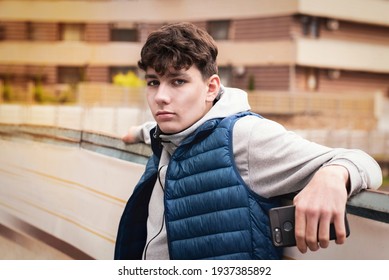 Portrait of a teenage guy in the city in spring, a guy holding a phone and waiting for a call from a friend to meet him, the guy has a sad face