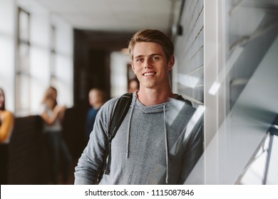 Portrait Of Teenage Male Student Standing Wall In Corridor Of A College. Caucasian Male Student In University Campus.