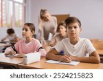 Portrait of teenage school girl and boy sitting together in classroom during lesson in secondary school