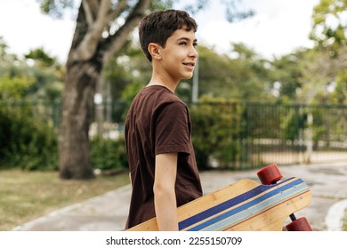 Portrait of a teenager boy holding his skateboard in the park - Powered by Shutterstock