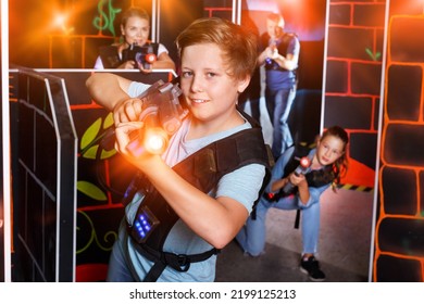 Portrait Of Teenager Boy With A Laser Gun Having Fun With Family On A Dark Lasertag Arena