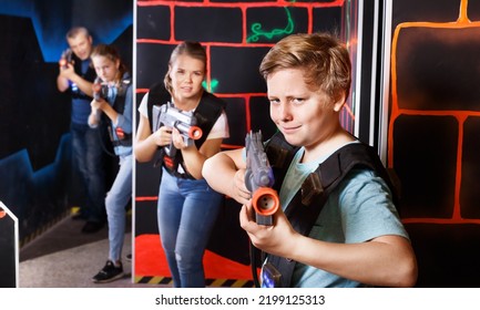 Portrait Of Teenager Boy With Laser Gun Having Fun With Family On Dark Lasertag Arena