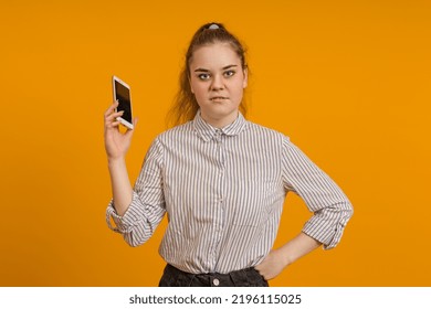 Portrait Of A Teenager Girl With A Mobile Phone In Her Hand On A Colored Background. Bad Conversation On The Phone