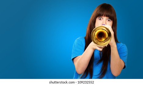 portrait of a teenager playing trumpet on blue background