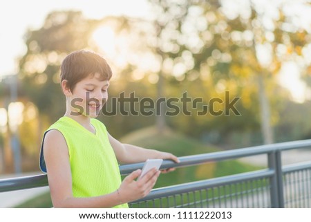 Teenager lächelnd, der sein Smartphone auf einem Basketballplatz aussieht.