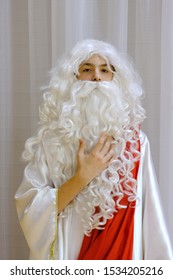 Portrait of a teenager with a white beard and a wig with curls. Cosplay for a costume show or halloween celebration. Carnival image of the ancient god or Greek ruler.