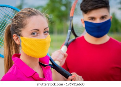 Portrait tennis players holding racket outside with protective masks - Close up girl and young boy who are playing tennis during quarantine covid19 holding racket in hand, preparing to play tennis  - Powered by Shutterstock