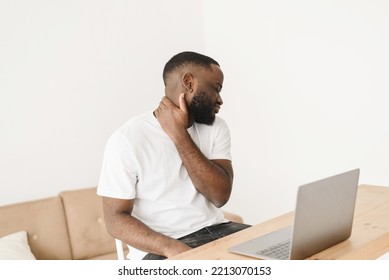 Portrait Of A Tense Handsome Black Man With Neck Pain. Man Working On Business Project Using Laptop Suffering From Neck Pain