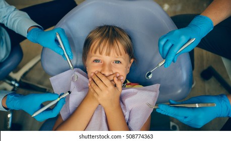 Portrait  Terrified Girl Scared At Dentist Visit, Siting In Chair, Screaming, Closed Mouth, Doesn't Want Dental Procedure 