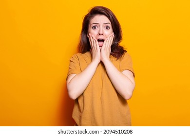 Portrait of terrified person holding hands on face to pose on camera. Scared woman screaming and being afraid, having anxious expression in studio. Frightened adult with emotions