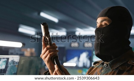 Portrait of terrorist loading gun, attacking enemy command center. Close up of masked insurgent reloading pistol during enemy base assault hijacking in guerilla warfare armed conflict, camera B