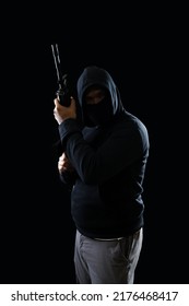 Portrait of a terrorist wearing a black hoodie holding a m16 rifle on a black background.concept of terrorism.