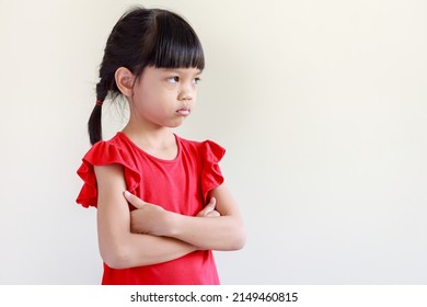 portrait of Thai Asian kid girl, age 4 to 6 years old, cute face, long hair. wearing a red shirt She stood with her arms crossed. looking sideways sad face scowling bad mood, isolated white background - Shutterstock ID 2149460815