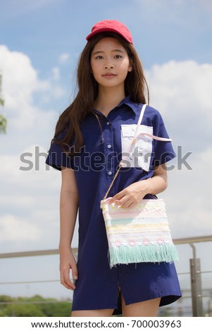 Portrait of thai teen beautiful girl blue dress red hat happy and relax