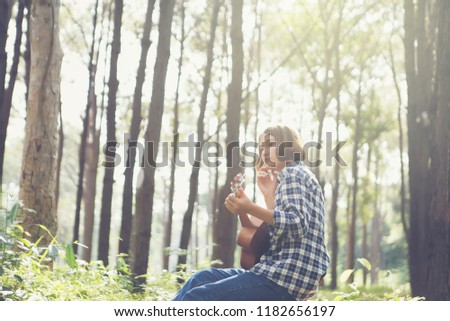Portrait of Thai-English Girl Her playing partners guitalele in the forest.
