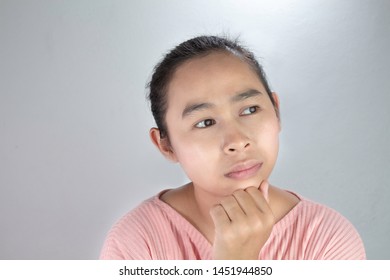 Portrait Thinking face of Asian young woman in pink shirt with hand on chin on grey background. - Shutterstock ID 1451944850