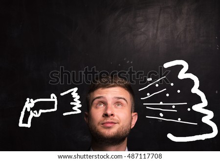 Portrait of thinking man on the background of blackboard on which is drawn a gun shot in the head