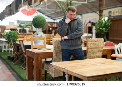 Portrait of thoughtful adult man contemplating about buying of furniture in store