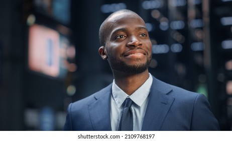 Portrait of Thoughtful Black Businessman wearing Suit, Standing in the Big City Business District Street, Posing and Smiling. Successful African American Digital Entrepreneur