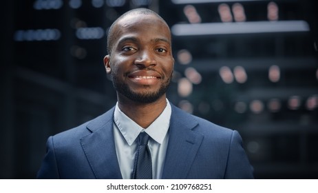 Portrait of Thoughtful Black Businessman wearing Suit, Standing in the Big City Business District Street, Looking at Camera and Smiling. Successful African American Digital Entrepreneur