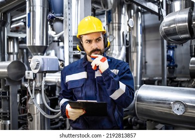 Portrait Of Thoughtful Caucasian Factory Worker Standing In Front Of Gas Pipes In Refinery.