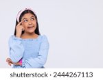 Portrait of thoughtful girl with hand on head standing against plain background