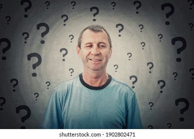 Portrait Of Thoughtful Middle Age Man Looking Suspicious Aside With A Distrust Smile. Puzzled And Doubtful Male Senior Keeps Has Multiple Question As Interrogation Marks Hang Around Head