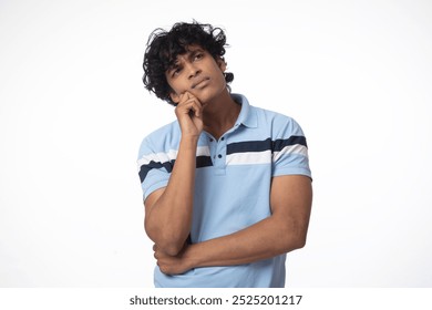 Portrait of thoughtful millennial Indian man in casual outfit, captured deep thinking while touching chin against white studio background, looking aside at copy space, panorama. Deep Thinking Student - Powered by Shutterstock