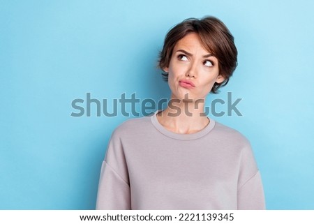 Portrait of thoughtful minded pretty girl short hairdo gray sweatshirt look empty space pouted lips isolated on blue color background