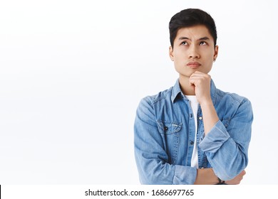 Portrait Of Thoughtful Smart Asian Man Thinking, Male Student Solving Puzzled, Look Up Complicated Or Pondering, Touch Chin While Trying Made-up Idea, Daydreaming Over White Background