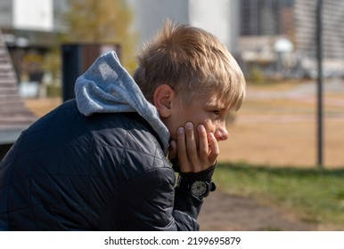 Portrait of thoughtful teenager sitting on park bench alone outdoors - Powered by Shutterstock
