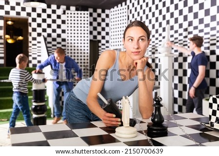 Portrait of a thoughtful young woman in a quest room, stylized as a chessboard