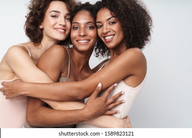 Portrait of three adorable multiethnic women smiling and hugging together isolated over white background