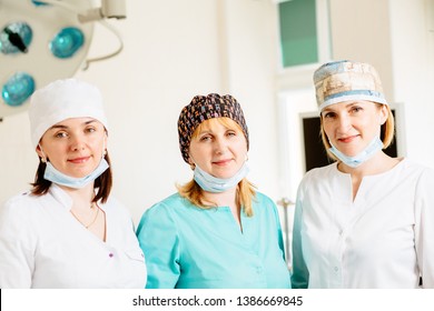 Portrait Of Three Beautiful Female Surgical Team Members Standing In Operating Theatre.