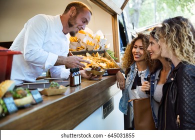 Portrait of three beautiful young women buying meatballs on a food truck in the park. - Powered by Shutterstock