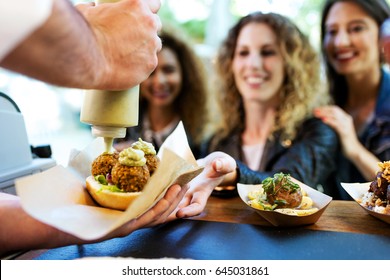 Portrait of three beautiful young women buying meatballs on a food truck in the park. - Shutterstock ID 645031861