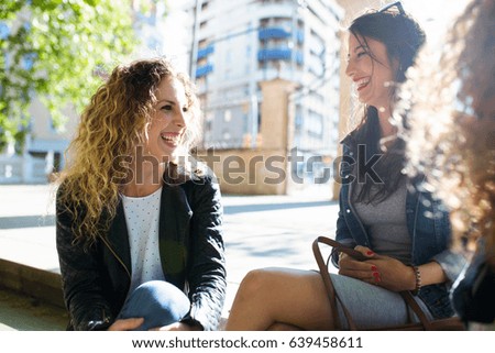 Portrait of three beautiful young women talking in the street.