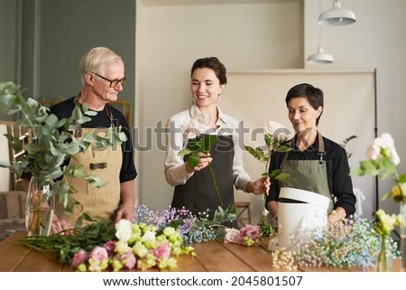 Portrait of three creative florists arraigning flower compositions in workshop